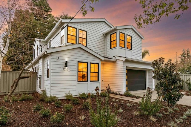 back house at dusk featuring a garage