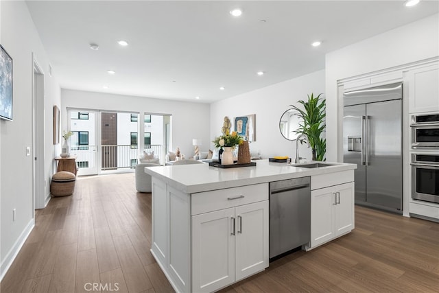 kitchen with dark hardwood / wood-style floors, sink, white cabinetry, a kitchen island with sink, and stainless steel appliances