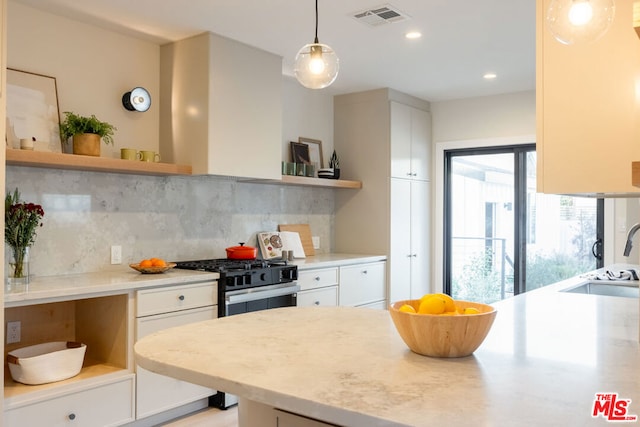 kitchen with gas range, sink, decorative light fixtures, and white cabinets