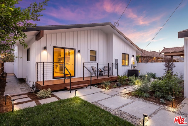 back house at dusk featuring central AC