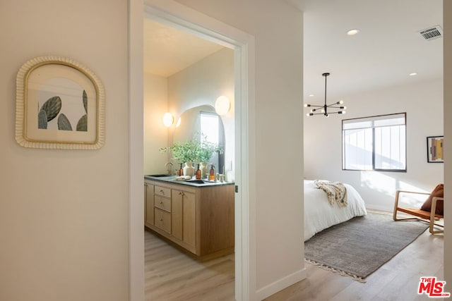 hall featuring a healthy amount of sunlight, sink, and light hardwood / wood-style flooring