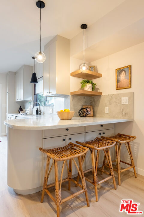 kitchen featuring a breakfast bar, white cabinetry, sink, decorative backsplash, and kitchen peninsula