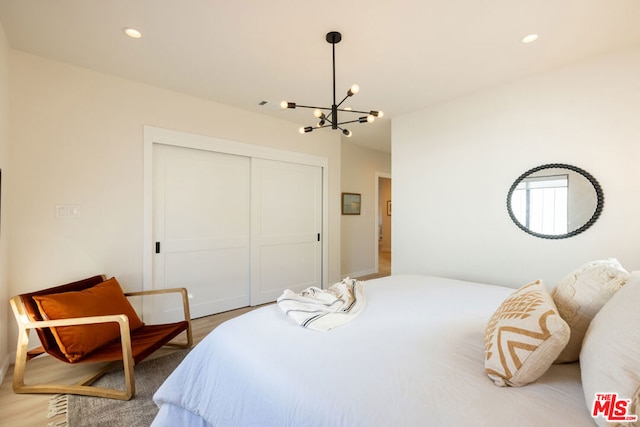 bedroom with hardwood / wood-style flooring, a chandelier, and a closet