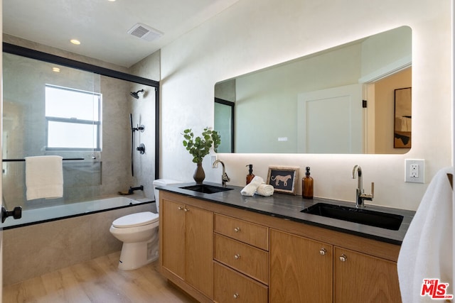 full bathroom featuring toilet, vanity, shower / bath combination with glass door, and hardwood / wood-style floors