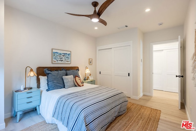 bedroom with light hardwood / wood-style flooring, ceiling fan, and a closet