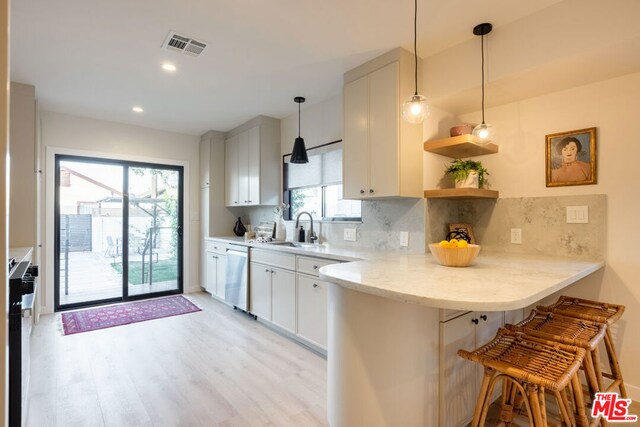 kitchen with decorative light fixtures, a breakfast bar, white cabinets, and kitchen peninsula