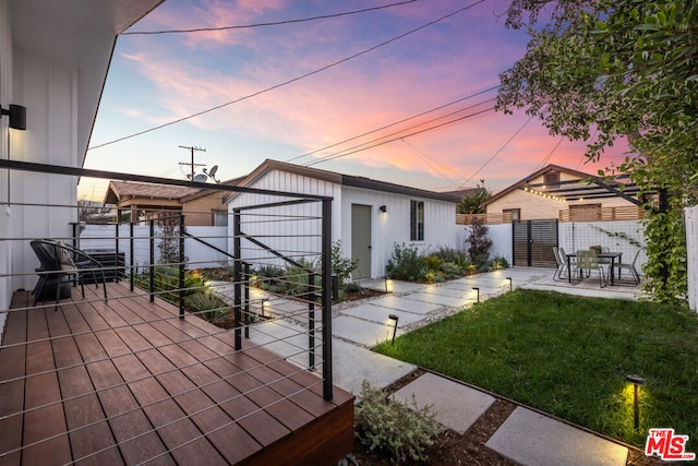 back house at dusk featuring a yard and a patio area