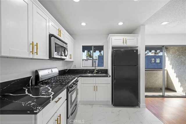 kitchen featuring white cabinets, appliances with stainless steel finishes, sink, and dark stone counters