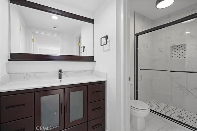 bathroom featuring toilet, a shower with door, and vanity