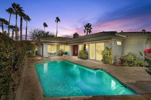 pool at dusk with a patio area