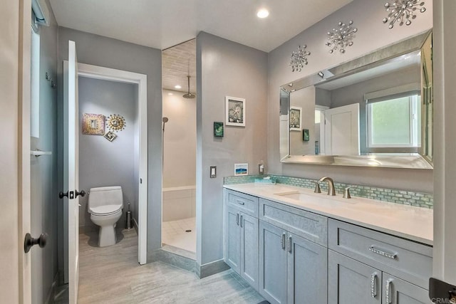 bathroom featuring a shower, toilet, vanity, and tasteful backsplash