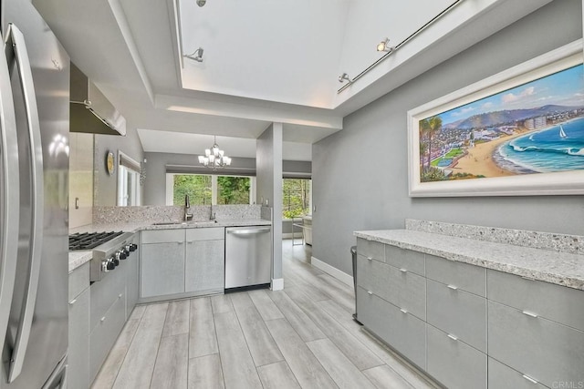 kitchen featuring appliances with stainless steel finishes, gray cabinetry, a chandelier, and light stone counters