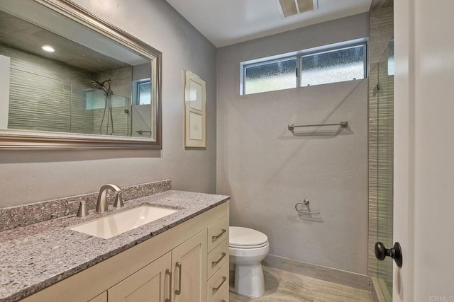 bathroom with a shower with shower door, vanity, and toilet