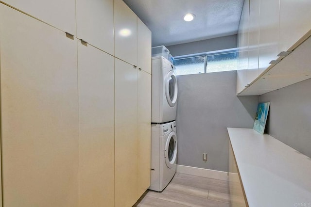 washroom featuring stacked washing maching and dryer and cabinets