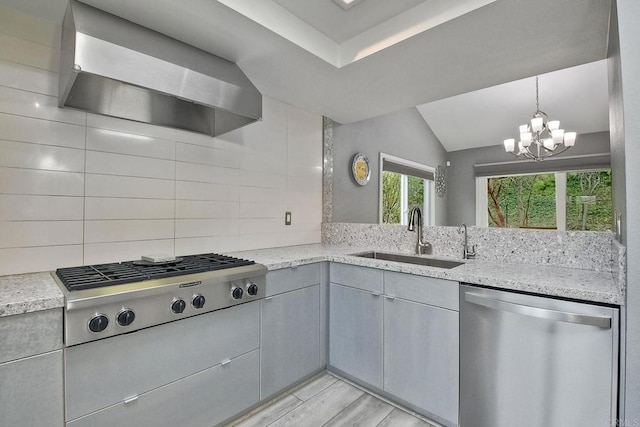 kitchen with wall chimney exhaust hood, stainless steel appliances, an inviting chandelier, sink, and backsplash