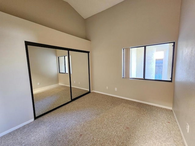 unfurnished bedroom with vaulted ceiling, a closet, and carpet flooring