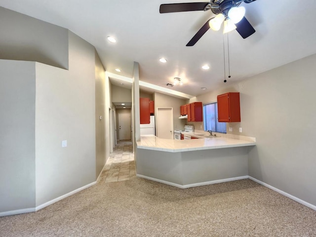 kitchen featuring kitchen peninsula, ceiling fan, white appliances, light colored carpet, and sink