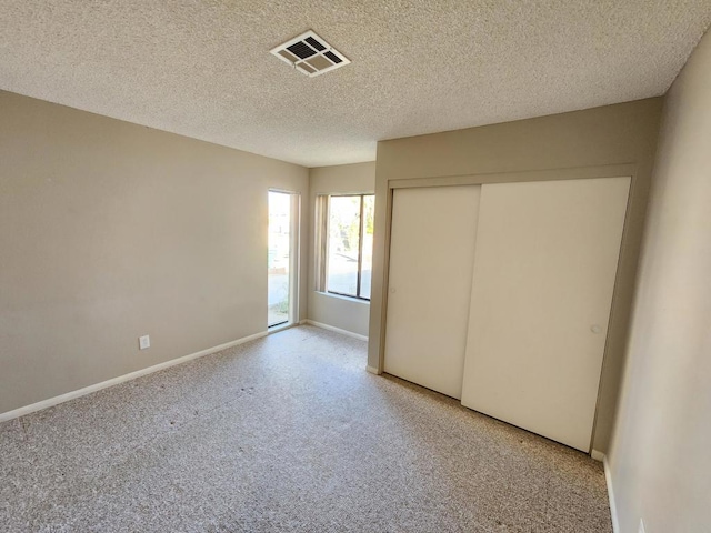 unfurnished bedroom featuring a textured ceiling, a closet, and light carpet