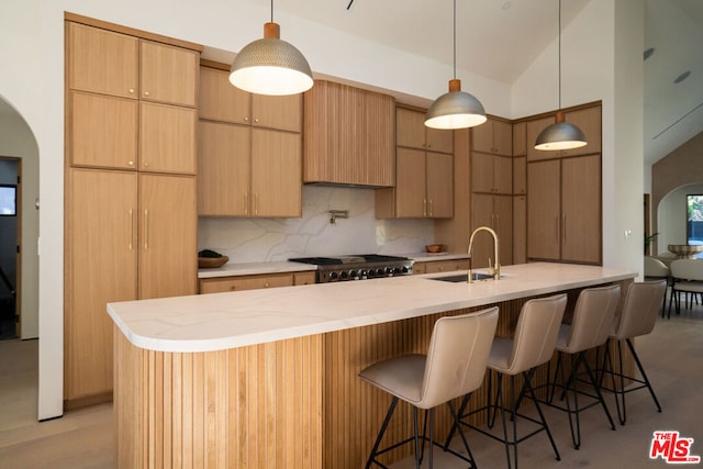 kitchen with decorative backsplash, stove, lofted ceiling, pendant lighting, and sink