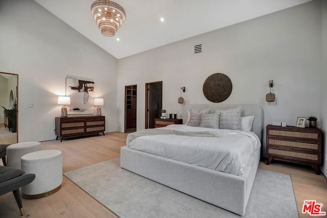 bedroom featuring a spacious closet, a closet, light hardwood / wood-style flooring, and high vaulted ceiling