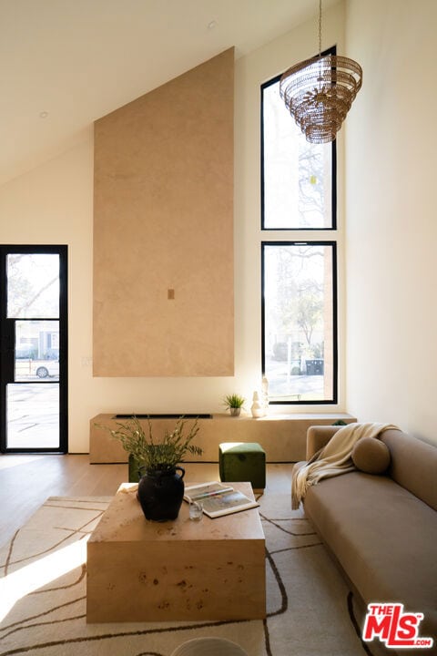 living room featuring high vaulted ceiling, an inviting chandelier, and light hardwood / wood-style floors