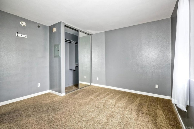 unfurnished bedroom with dark colored carpet and a closet