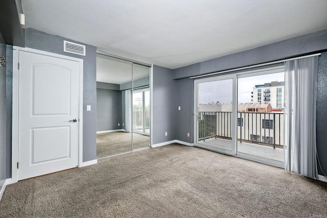 unfurnished bedroom featuring access to outside, a closet, and carpet floors