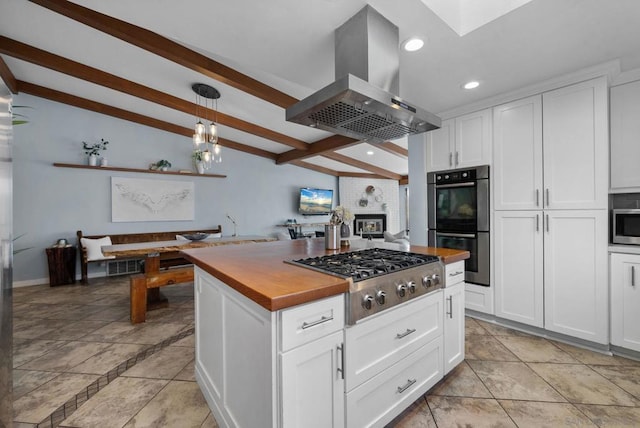 kitchen featuring pendant lighting, island exhaust hood, stainless steel gas cooktop, and white cabinets