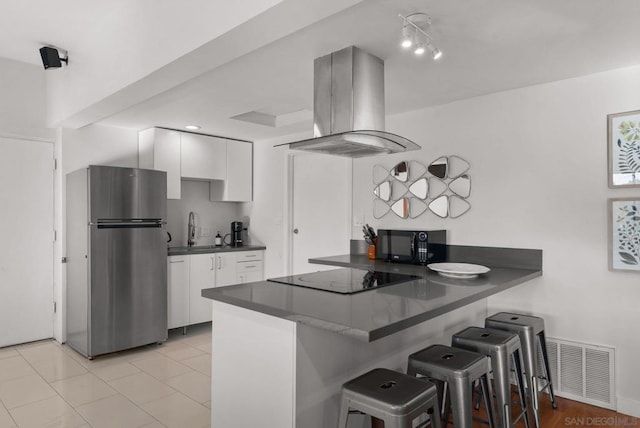 kitchen featuring island exhaust hood, kitchen peninsula, white cabinets, and black appliances