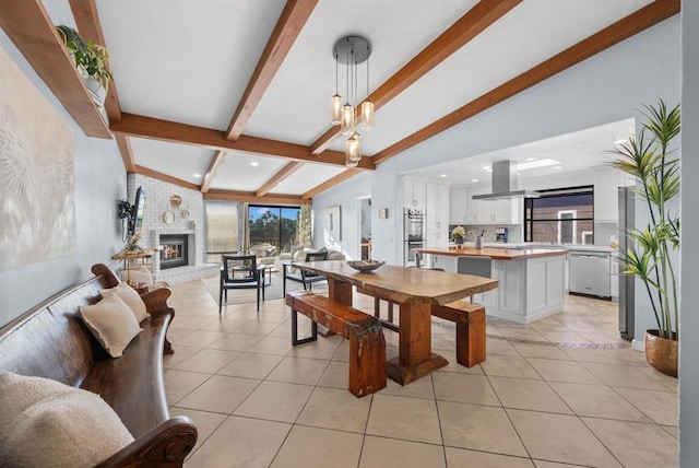 tiled dining room featuring lofted ceiling with beams and a fireplace