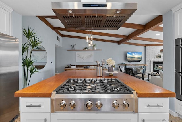 kitchen with a brick fireplace, stainless steel appliances, and white cabinets