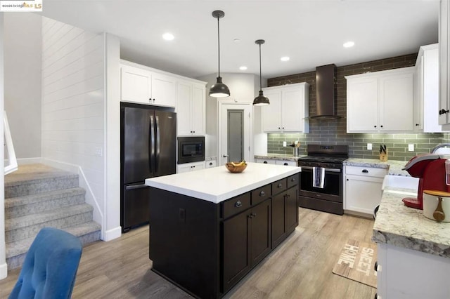 kitchen with white cabinetry, wall chimney range hood, black appliances, and a center island