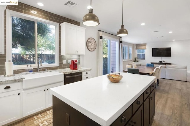 kitchen with white cabinetry, black dishwasher, decorative light fixtures, a kitchen island, and sink