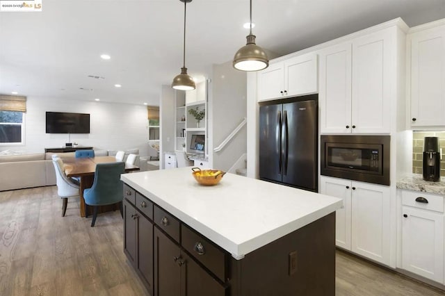 kitchen featuring white cabinetry, black microwave, hanging light fixtures, dark hardwood / wood-style floors, and refrigerator