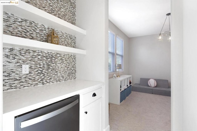 interior space featuring light carpet, white cabinetry, tasteful backsplash, beverage cooler, and pendant lighting