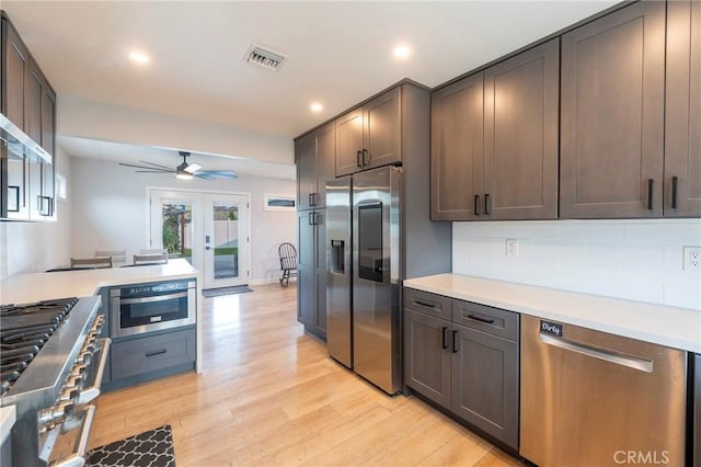 kitchen with ceiling fan, appliances with stainless steel finishes, tasteful backsplash, french doors, and light hardwood / wood-style flooring