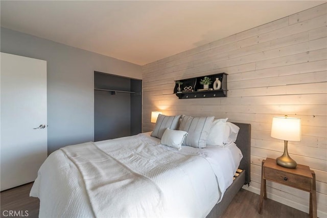 bedroom with dark wood-type flooring, a closet, and wooden walls