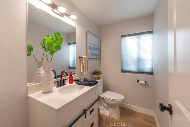 bathroom with toilet, a wealth of natural light, hardwood / wood-style flooring, and vanity