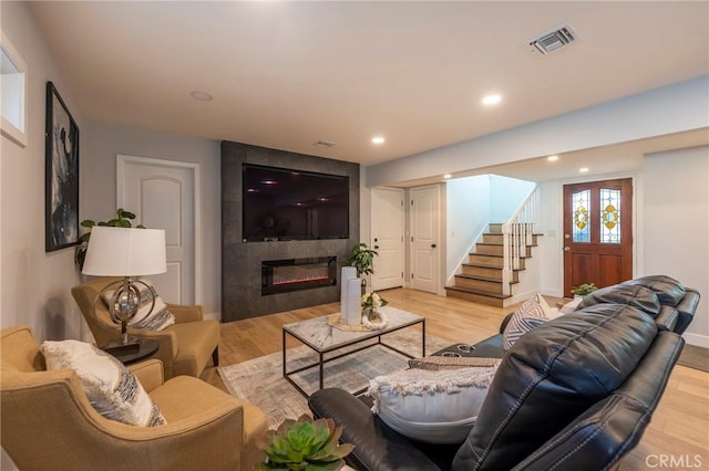 living room with a tile fireplace and light wood-type flooring