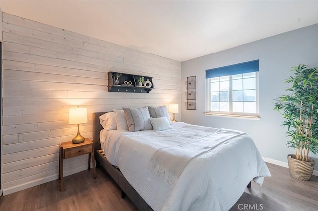 bedroom featuring dark wood-type flooring and wood walls