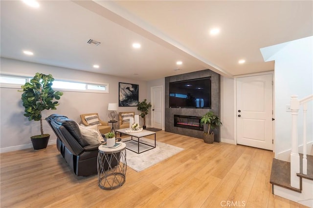 living room featuring light hardwood / wood-style flooring and a tiled fireplace