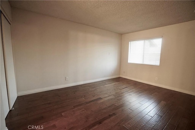 unfurnished room featuring a textured ceiling and dark wood-type flooring