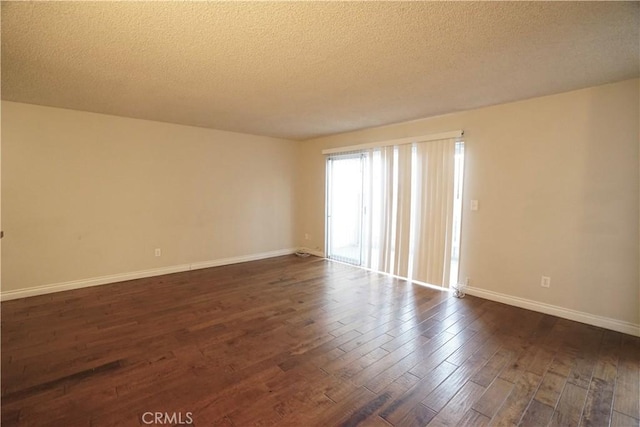 unfurnished room with dark wood-type flooring and a textured ceiling