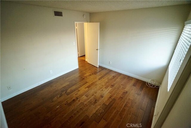 unfurnished room featuring dark hardwood / wood-style floors and a textured ceiling