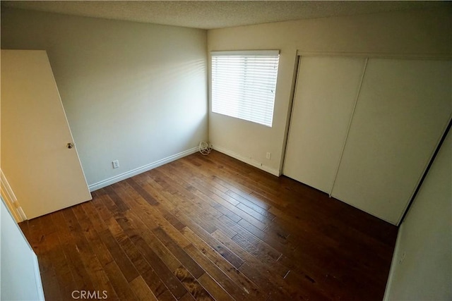 unfurnished room featuring a textured ceiling and dark hardwood / wood-style flooring