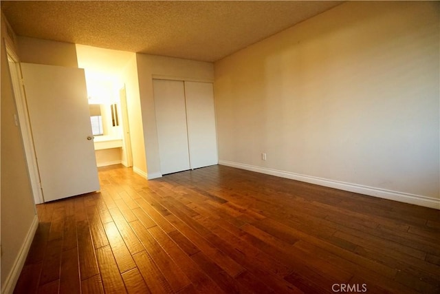 unfurnished bedroom featuring a textured ceiling, a closet, and dark hardwood / wood-style floors