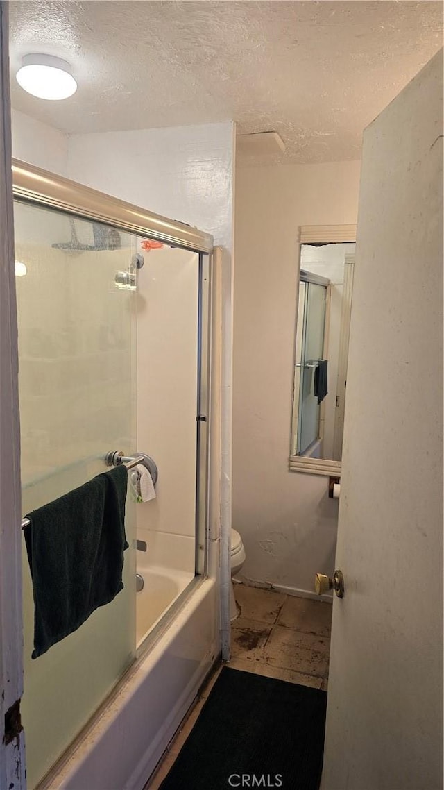 bathroom with toilet, shower / bath combination with glass door, and a textured ceiling