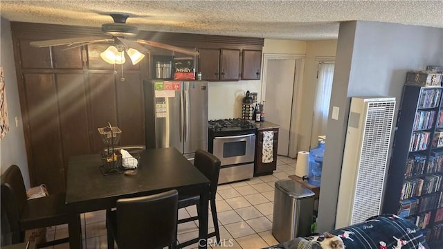 kitchen with appliances with stainless steel finishes, light tile patterned floors, ceiling fan, dark brown cabinetry, and a textured ceiling