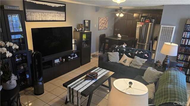 living room with a textured ceiling, ceiling fan, and light tile patterned floors