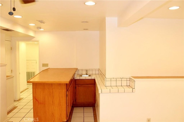 kitchen with sink, light tile patterned floors, and kitchen peninsula